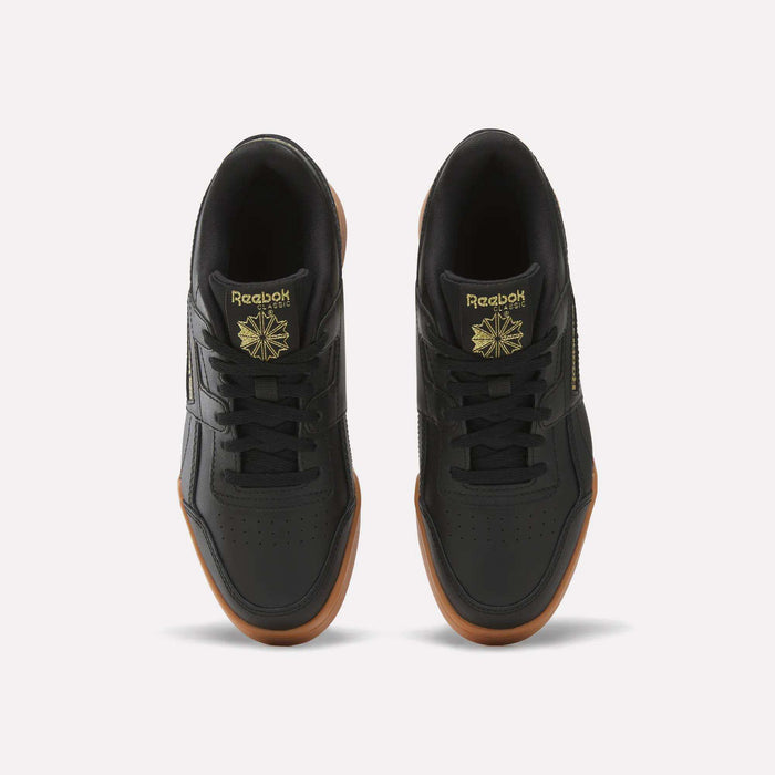 Top view of Reebok Workout Plus Shoes for big kids in black with brown gum soles, gold branding, and a star logo on the tongue, side by side on a white background—a sporty pick for juniors.