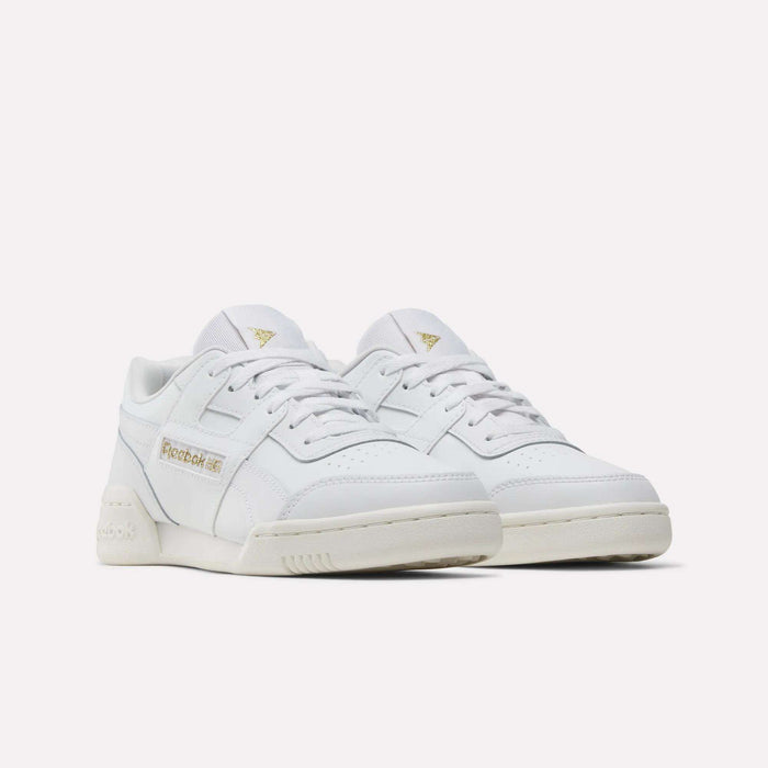 A pair of Reebok Workout Plus Shoes for big kids in white with gold logo accents on the side and tongue, stylishly displayed on a white background—perfect for juniors who want classic sporty style.