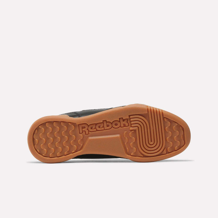 The image displays the gum rubber sole of Reebok Workout Plus Shoes for Big Kids, viewed from below. The sole features the Reebok logo and a textured grip pattern with wavy and circular lines.
