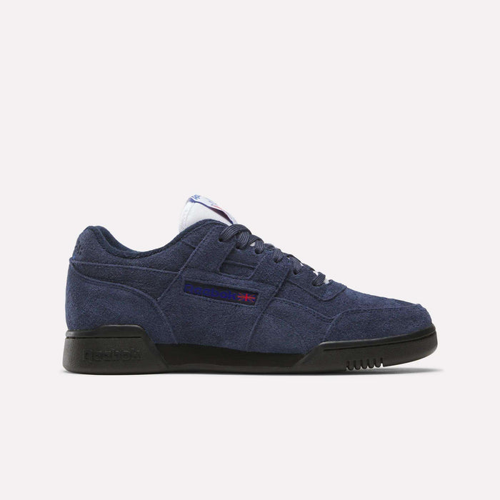 A navy blue suede Reebok Workout Plus shoe with a black sole, blue laces, and side Reebok logo with Union Jack captures classic '80s fitness style, displayed on a clean white background.