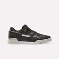 The Reebok Workout Plus Shoes are black leather low-tops with a white sole and subtle white and gray accents. Stylish for workouts, they display the Reebok logo and flag on the side.