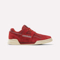 A pair of Reebok Workout Plus Shoes in Heritage Red and Paperwhite is displayed on a plain white background. These archive-inspired sneakers from Reebok feature a premium heritage red suede upper, complemented by a cream-toned sole, white stitching, and classic Reebok logos on the side and tongue for iconic, timeless style.