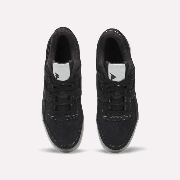 A pair of Reebok Workout Plus Shoes in black with white stitching and tongue labels, seen from above on a light background. The tied laces and side-by-side placement highlight their classic '80s-inspired fitness style.