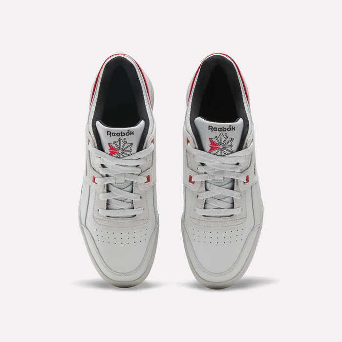 A top-down view of a pair of Reebok Workout Plus shoes in white with red accents and the Reebok logo on the tongue, featuring subtle vintage details against a plain light gray background.