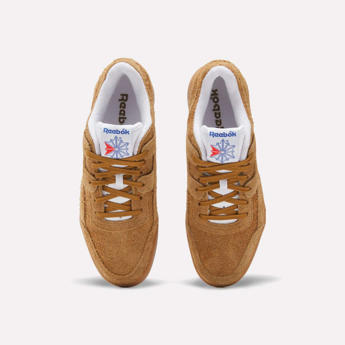 Top view of Reebok Workout Plus Shoes in brown suede, featuring white lining, brown laces, and a blue and red Reebok logo on the white tongue. The sneakers are placed side by side on a light background.