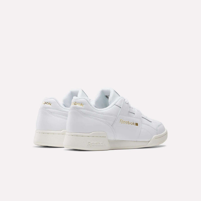 A rear side view of Reebok Workout Plus Shoes in white with gold branding, off-white soles, and classic low-top ‘80s fitness style on a plain white background.