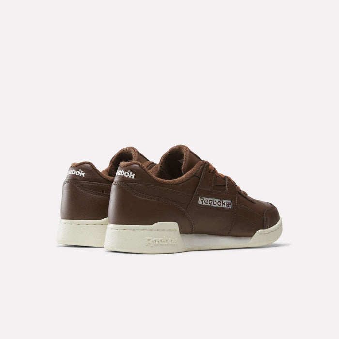 A pair of brown Reebok Workout Plus Shoes with cream-colored soles, shown from the back and side on a light background—these classic sneakers from Reebok seamlessly blend style and comfort.