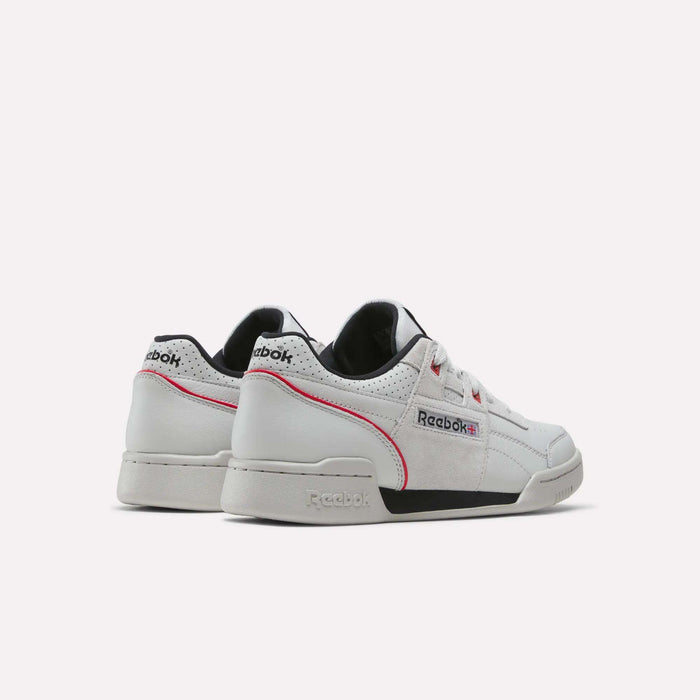 A pair of Reebok Workout Plus Shoes in white, featuring black and pink accents, are displayed against a light background. One shoe is positioned to show the back while the other faces forward, highlighting the Reebok branding and vintage-inspired design details.