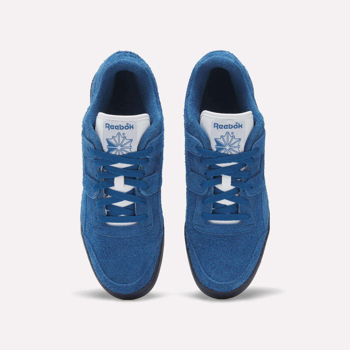 Top view of Reebok Workout Plus Shoes in blue, showing white tongues with the Reebok logo and dark outsoles, placed side by side on a white background—a classic '80s fitness style from Reebok.