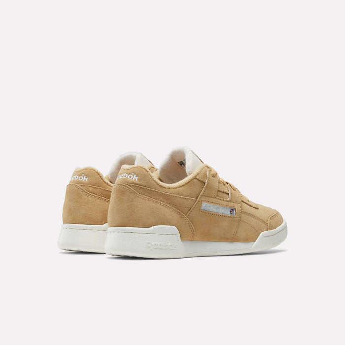 A pair of tan suede Reebok Workout Plus Shoes with white soles is angled on a light background, featuring the iconic Reebok logo on the side and heel that highlights the classic '80s fitness style.