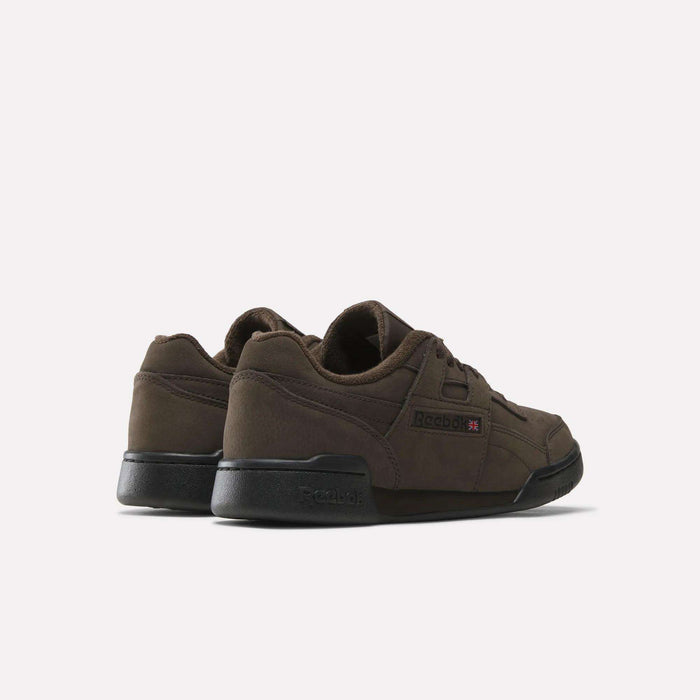A pair of Reebok Workout Plus Shoes in brown, featuring black soles, captured from the back and side angles against a plain white background—these classic sneakers combine enduring style with exceptional comfort.
