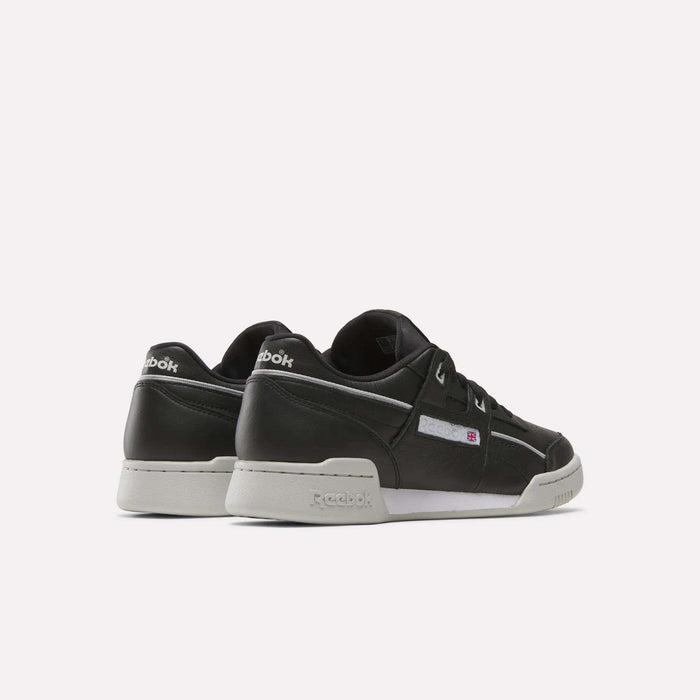 A pair of Reebok Workout Plus Shoes in black leather with white soles, displayed from the rear on a light background. The shoes feature Reebok branding on the heel, side, and tongue.