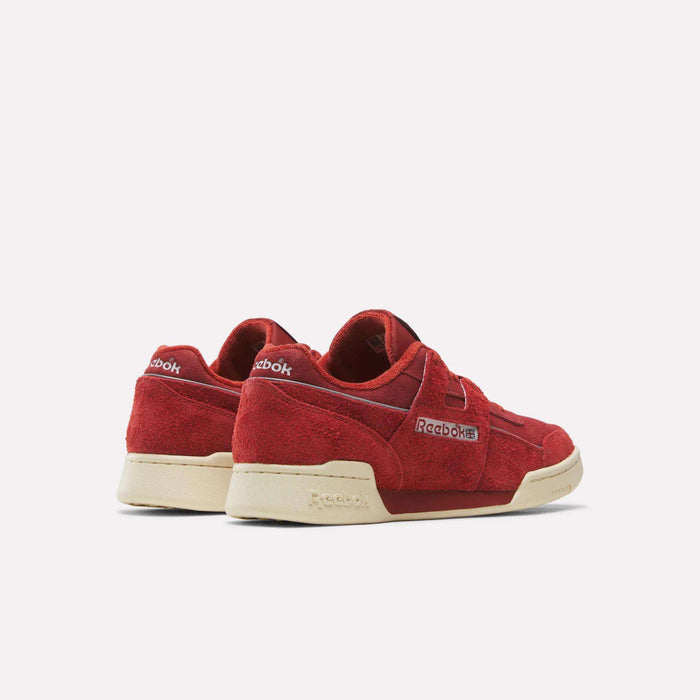 A pair of Reebok Workout Plus Shoes, inspired by the brand’s archives, featuring a rich red suede upper and beige soles, displayed from the back and side against a plain white background.