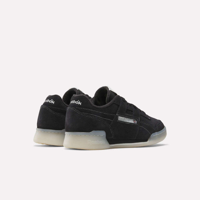 The Reebok Workout Plus Shoes feature a black suede finish, translucent rubber soles, and silver Reebok branding—reviving '80s fitness style on a clean white background.