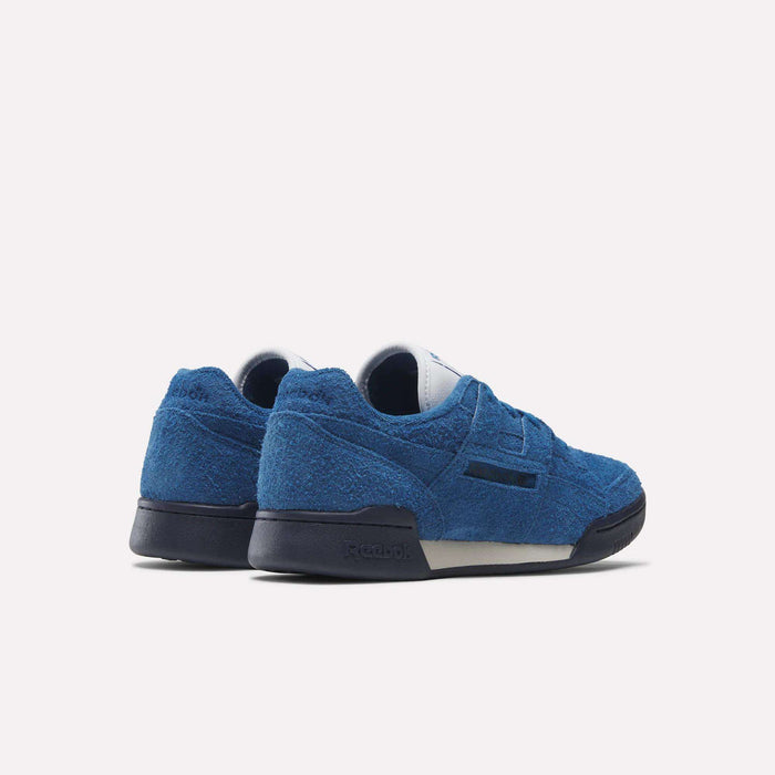 A pair of Reebok Workout Plus Shoes in blue with navy soles, shown from the back and side, evoke '80s fitness style against a plain white background.