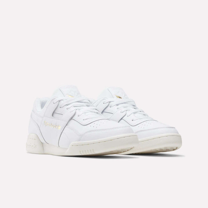 A pair of Reebok Workout Plus Shoes with gold branding, white laces, and off-white soles are displayed on a plain light background, capturing the classic '80s fitness style.
