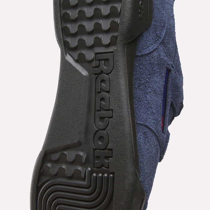 Close-up of the sole on Reebok Workout Plus Shoes, featuring the embossed Reebok logo in black rubber, distinctive tread patterns, and hints of blue fabric upper—reflecting classic 1980s fitness style.