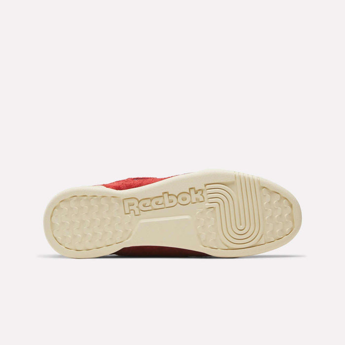 The image displays the beige sole of the Reebok Workout Plus Shoes, featuring the signature Reebok logo and textured grip patterns as seen from underneath. Part of the red upper—with suede accents—can be seen, showcasing the archive-inspired design of these classic Reebok sneakers.