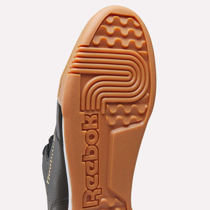 Close-up of the sole of Reebok Workout Plus Shoes, featuring an orange outsole with the Reebok logo and a textured tread pattern—a classic tribute to ‘80s fitness style.