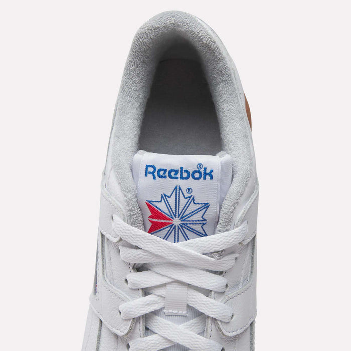 Top view of Reebok Workout Plus Shoes features gray lining, white laces, and a blue Reebok logo with a red and blue star on the tongue—a classic tribute to '80s fitness heritage.