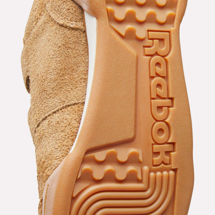 Close-up of the sole of Reebok Workout Plus Shoes, highlighting textured rubber with the Reebok logo and detailed tread for grip. The rough suede upper nods to '80s fitness style while offering practical design.