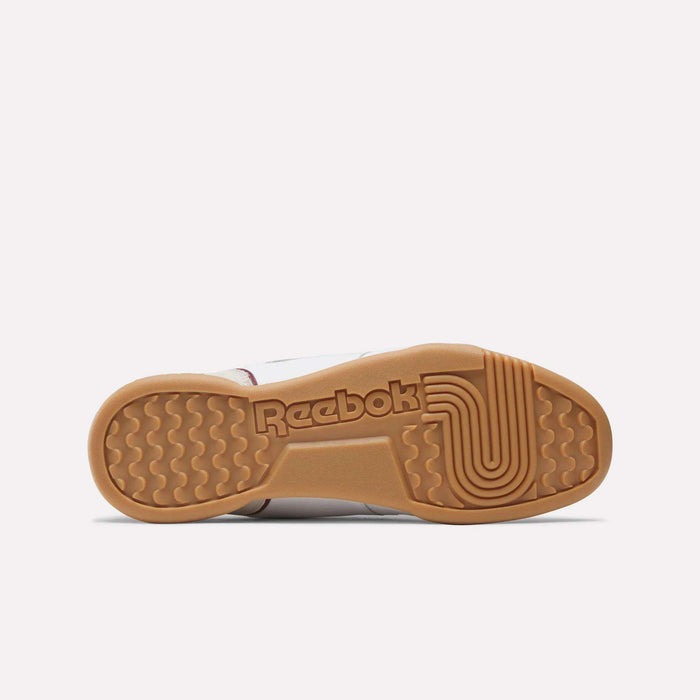 The image displays the sole of Reebok Workout Plus Shoes, featuring a tan rubber outsole with wavy and circular grip patterns inspired by classic '80s fitness style, and the Reebok logo embossed at the center.