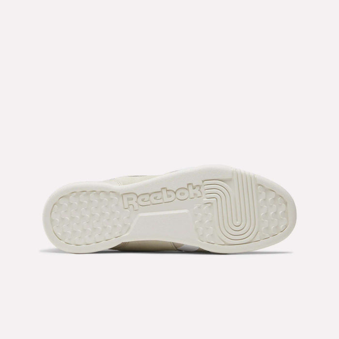 The image displays the outsole of the Reebok Workout Plus Shoes, showcasing the Reebok branding at the center and textured detailing on both the toe and heel sections. The sole features an off-white hue, emphasizing the timeless style characteristic of Reebok leather footwear.
