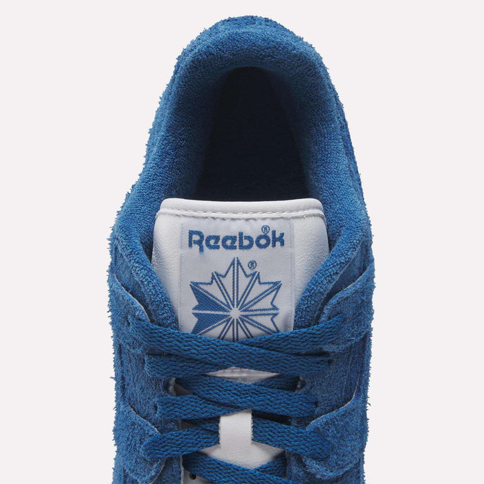 Top view of Reebok Workout Plus Shoes in royal blue suede, with blue laces and a white tongue featuring the Reebok logo and starburst design—a classic nod to '80s fitness style.