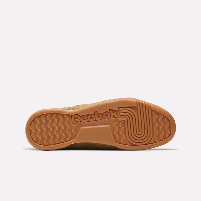 The image shows the sole of a tan Reebok Workout Plus Shoe, featuring the Reebok logo and a unique tread with wavy and circular grooves on a gum rubber sole, reflecting classic '80s workout style.