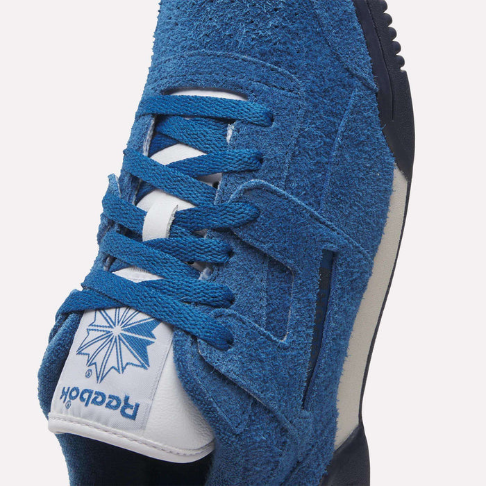 Close-up of Reebok Workout Plus Shoes in blue suede with blue laces and a white tongue featuring the blue Reebok logo and starburst design. This classic '80s-inspired workout sneaker has a white midsole with dark accents.
