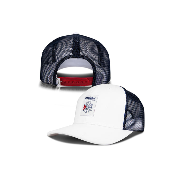 The Reebok Woven Patch Vector Trucker Cap is shown in white and navy, with a front woven Reebok logo patch and a red adjustable snapback closure at the back for a secure fit.