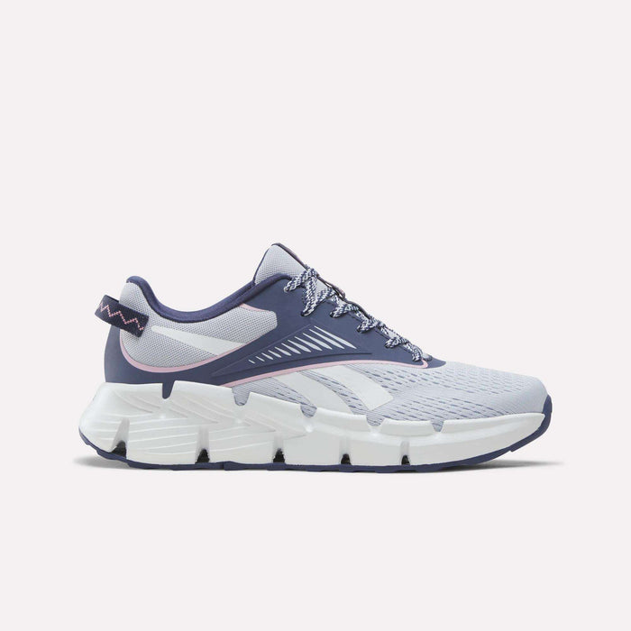 A pair of Reebok Zig Dynamica 6 Running Shoes for big kids in Legacy Blue, Tranquil Blue, and Expressive Pink, featuring mesh fabric construction, patterned laces, and a thick segmented white sole with advanced Zig technology—displayed on a light background and ideal for those after dynamic energy return.