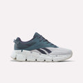 The Reebok Zig Dynamica 6 Running Shoes for Big Kids in Dark Indigo, Midnight Tide, and New Grey 1 feature a mesh upper, chunky white speckled sole with Zig technology, and the Reebok logo on the side, displayed against a plain white background.