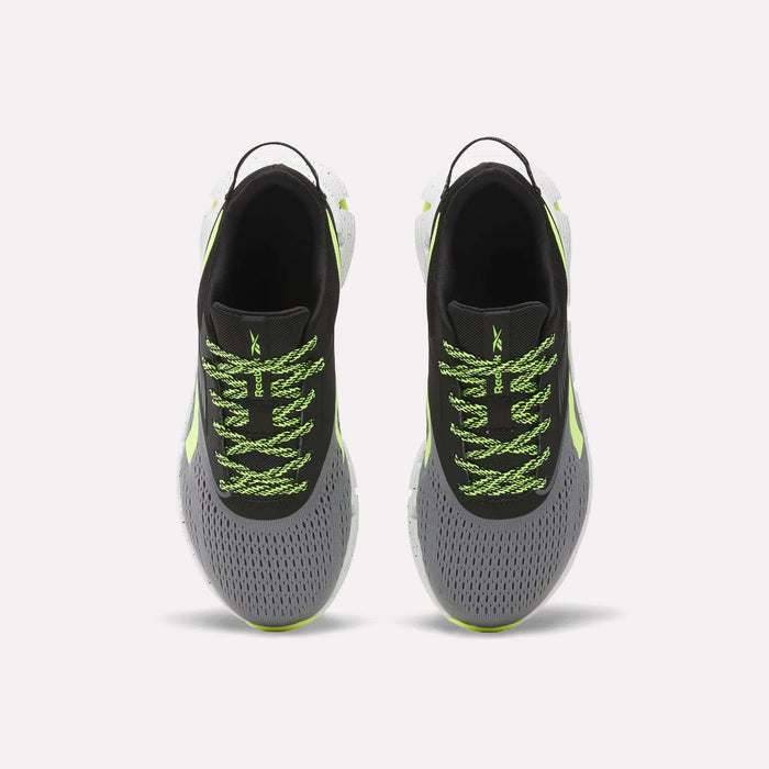 A pair of Reebok Zig Dynamica 6 Running Shoes for big kids, in gray with black interiors, neon green patterned laces, Zig technology soles, and light green accents, displayed from above on a plain white background.
