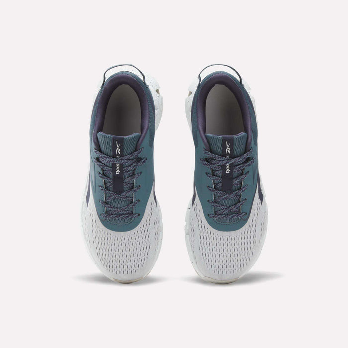 A pair of Zig Dynamica 6 Running Shoes for big kids by Reebok in teal and white, viewed from above to display their mesh fabric, laces, and the Reebok logo on each tongue. Featuring innovative Zig technology, these athletic shoes offer a perfect blend of comfort and style for active lifestyles.