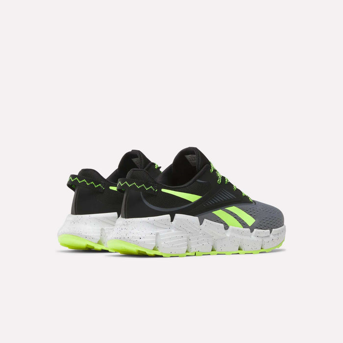 The Reebok Zig Dynamica 6 Running Shoes for big kids feature black and gray uppers with neon green accents, zigzag details, and thick white speckled soles with Zig technology and neon green outsoles, shown on a plain white background.