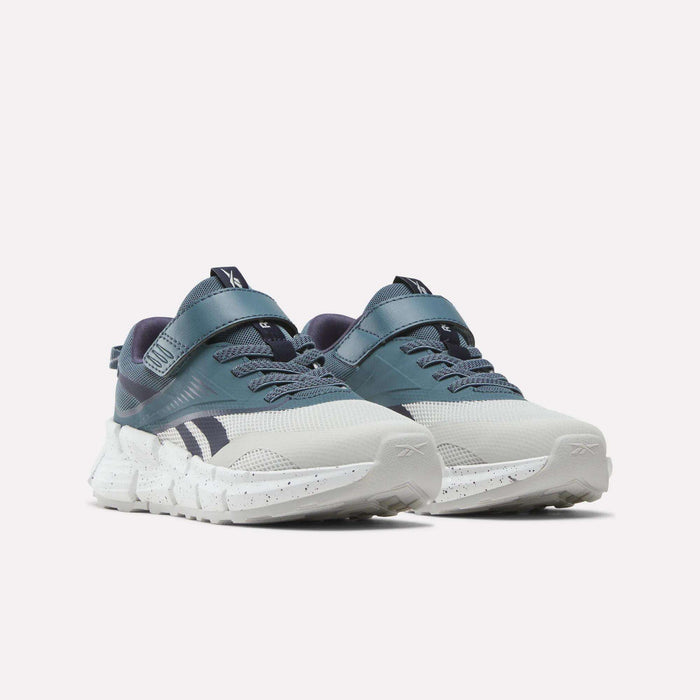 A pair of Reebok Zig Dynamica 6 Running Shoes for little kids in blue and white, featuring thick speckled soles, Velcro straps, and Zig technology, displayed on a plain white background.