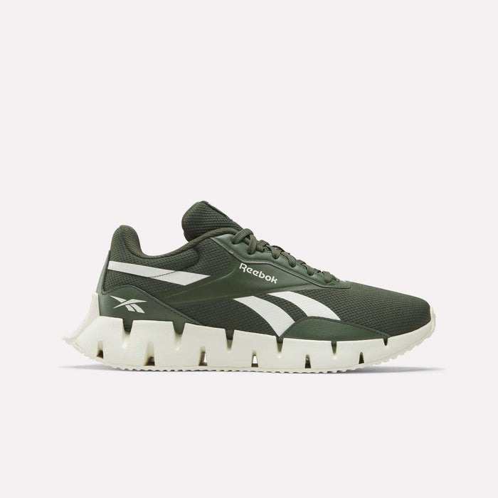 The Zig Dynamica STR Shoes by Reebok feature an olive green mesh upper, white jagged sole, and white side stripes, displayed in a side profile against a plain light background.