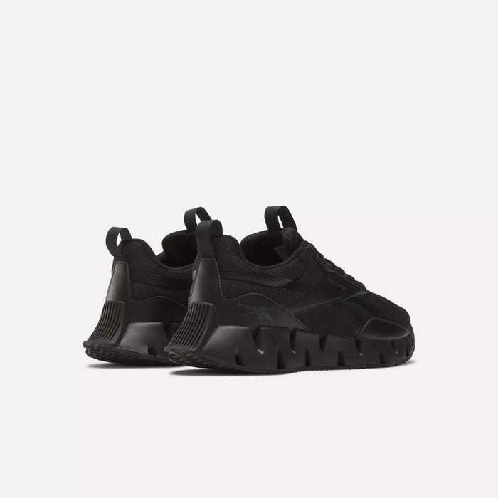 The Reebok Zig Dynamica STR Shoes, shown in black with chunky sculpted soles and heel pull tabs, are angled from the back on a white background—perfect progressive running shoes for both style and support.