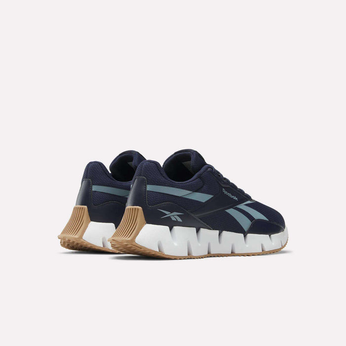 The Reebok Zig Dynamica STR Shoes feature a navy mesh upper, light blue side stripes, chunky white zigzag soles, and tan rubber outsoles, shown against a plain white background.