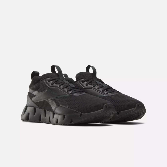 The Reebok Zig Dynamica STR Shoes feature chunky, textured soles and mesh uppers in black, with matching laces and subtle design accents. Displayed on a plain white background, these running shoes deliver a modern, stylish look.