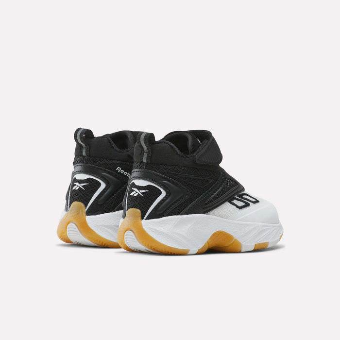A pair of Reebok Zone Breaker Shoes for toddlers is displayed at an angle, highlighting the heels and outer sides. These sneakers feature a bold mix of black, white, and orange colors, a chunky white sole, and a secure Velcro strap. Designed for toddler boys, they offer supportive ankles to ensure comfort and stability during active play.